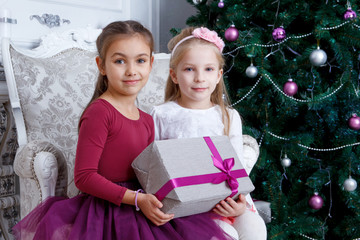 Girls holding big gift-box under Christmas tree