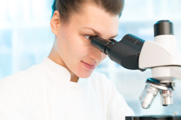 Sticker - Young woman in biological laboratory with trinocular mivroscope  Attractive young female scientis. Scientist using a microscope in a laboratory