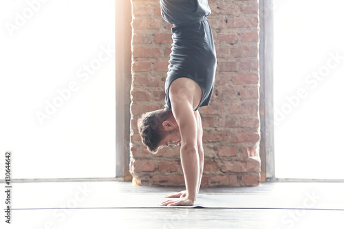 Fotografia Sport. Strong young athlete doing exercise. Handstand