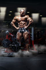 Wall Mural - very power athletic guy standing with barbell, workout in the gym