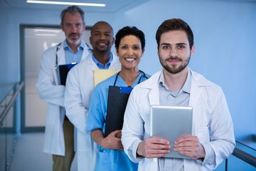 Wall Mural - Portrait of male doctors and nurse standing in corridor