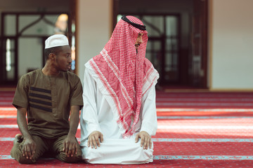 Two religious muslim man praying together inside the mosque