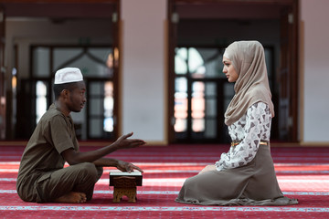 Black Muslim man and woman praying in mosque