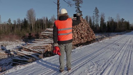 Wall Mural - Lumberjack with chainsaw take pictures on smart phone