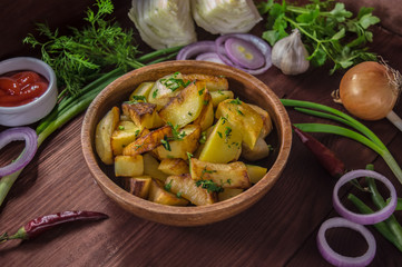 Roasted potatoes with vegetables and herbs on a wooden background, top view. Close-up