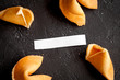 Chinese fortune cookie with prediction on dark background top view
