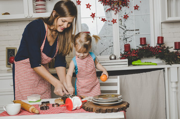 Happy mother and little daughter making Christmas cookies on kitchen