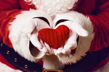 Wall Mural - Santa Claus holding red knitted heart in both hands