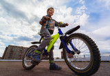 Fototapeta  - Small smiling child and bike in the city. Urban concept.  Focus on boy
