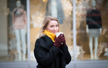 Portrait of young Caucasian woman with coffee in front of appare