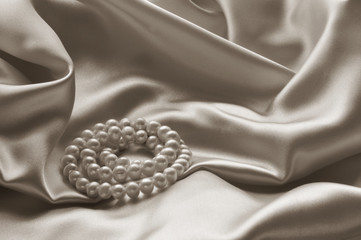 Detail of draped beige silk fabric with pearl jewelry