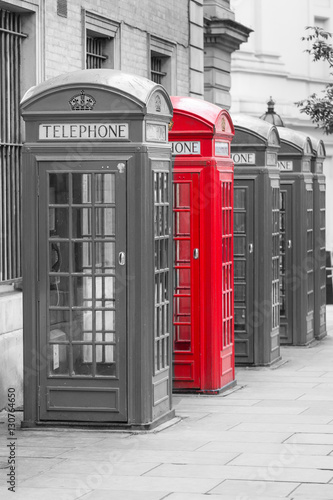 Fototapeta na wymiar Five Red London Telephone boxes in portrait in black and white with one red