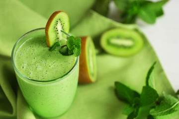 Fototapete - Glass of kiwi smoothie on green napkin