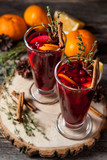 Fototapeta  - Two glasses of hot mulled wine on a dark background. Spices, oranges and fir cones