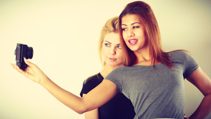 Two models girls taking self picture with camera