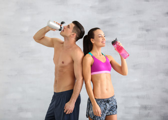 Wall Mural - Young sporty couple drinking water in gym