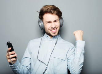 Wall Mural - young man wearing headphones and holding mobile phone 