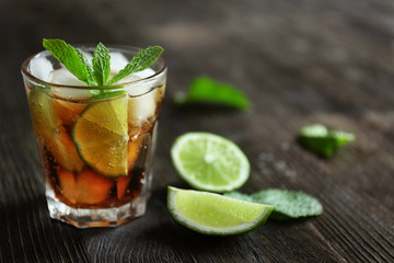 Poster - Glass of cocktail with ice and mint on wooden table closeup