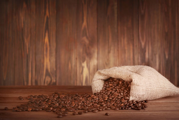 Poster - Purse with roasted coffee beans on wooden background