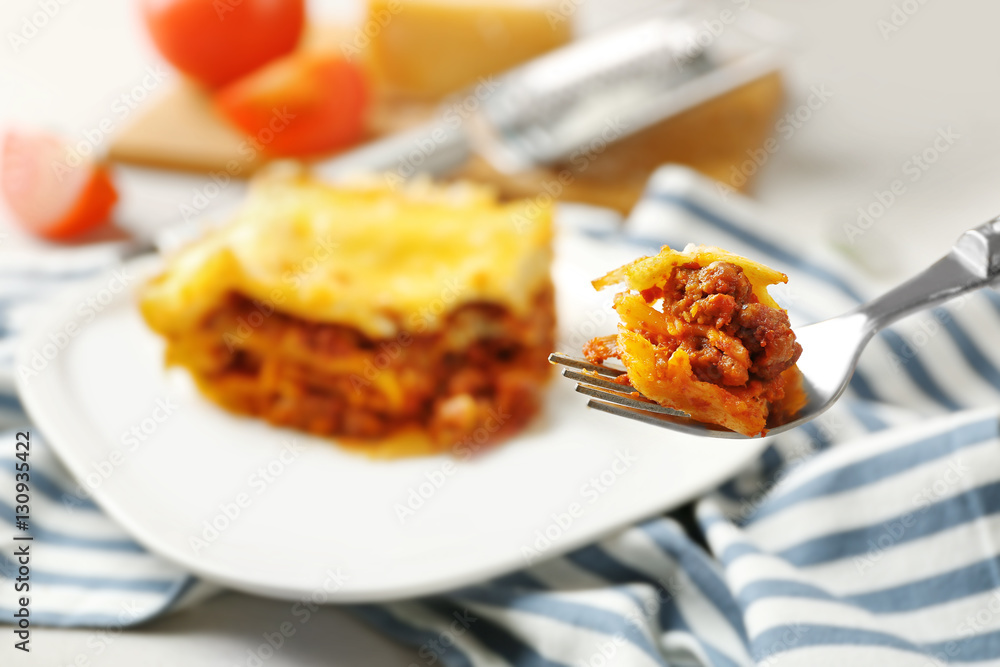 Plate with delicious lasagna and striped napkin, closeup