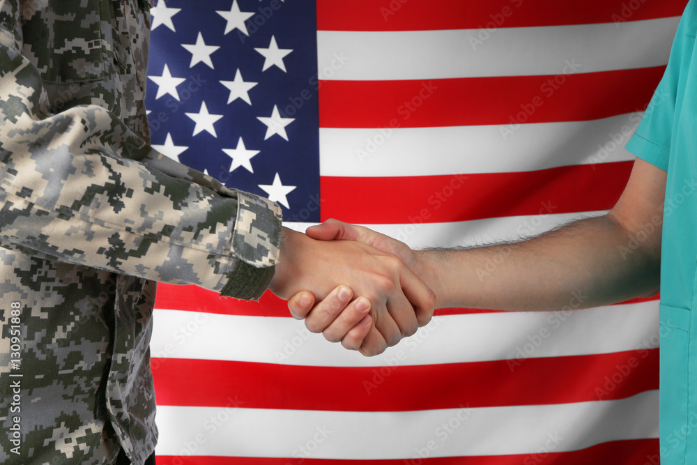 Soldier and doctor shaking hands on American flag background