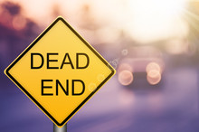 Dead End Warning Sign On Blur Traffic Road With Colorful Bokeh Light Abstract Background.