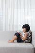 Leinwandbild Motiv Asian Chinese little girl lying on the sofa with phone