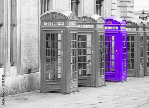 Fototapeta na wymiar Five Red London Telephone boxes all in a row, in black and white with one booth in purple