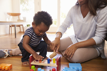 Mother And Son Playing With Toys On Floor At Home