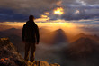 Man standing on the top of a mountain watching sunset sunrise