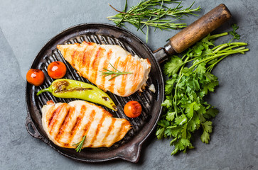 Grilled chicken fillets, chili and tomatoes on grill iron pan