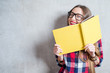 © rh2010 - Portrait of a young happy student in checkered shirt with yellow book on the gray wall background