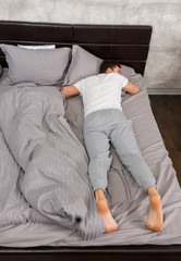 Young tired male in pajama sleeping without blanket in stylish b