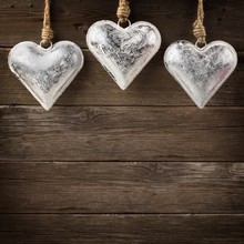 Rustic Metal Heart Ornaments Hanging Against A Vintage Wooden Background