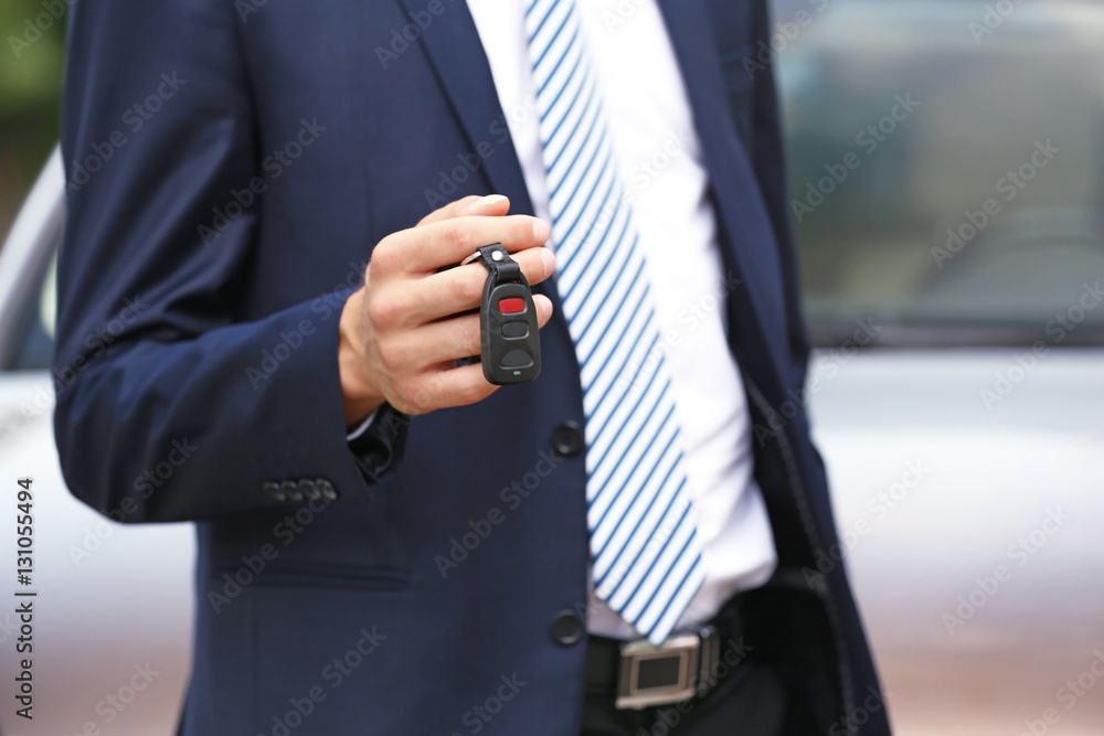Man using car alarm key on car blurred background