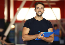 Portrait Of Personal Trainer Holding Clipboard With Training Plan In Gym
