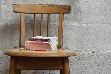 Old books on wooden chair with concrete wall vintage background