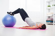 © undrey - sporty woman doing pilates exercise lifting her pelvis with fit ball at home.