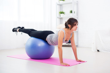 Sporty woman doing stretching fitness exercise on ball