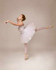 Wall Mural - Young beautiful ballerina dancing on light background