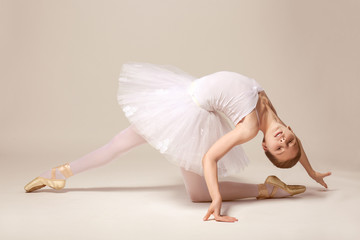 Wall Mural - Young beautiful ballerina dancing on light background
