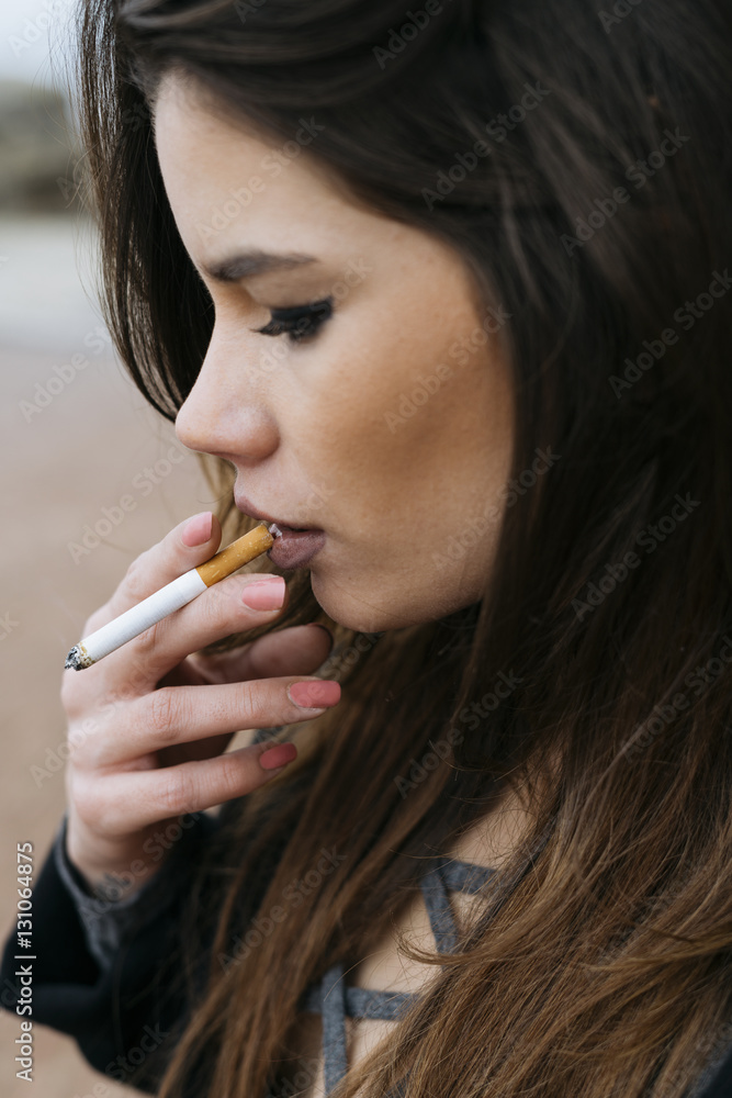 Woman holding cigarette to mouth Stock Photo