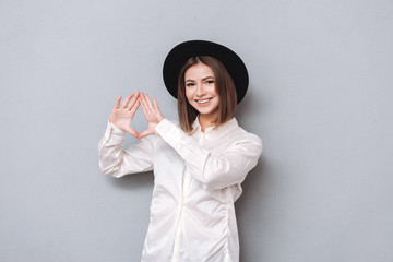 Wall Mural - Smiling young woman in hat and shirt showing hand gesture