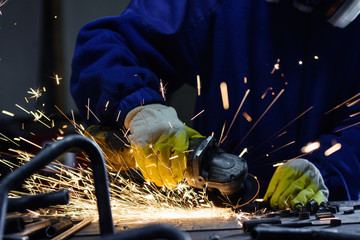 Worker cutting metal on ad work table by angle grinder machine