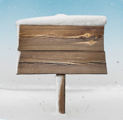 Wooden signpost with less snow on it and snowfall