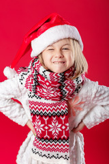 little girl in santa hat and scarf on red background