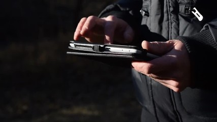 Close-up of hands of an adult man using tablet in forest with special lighting