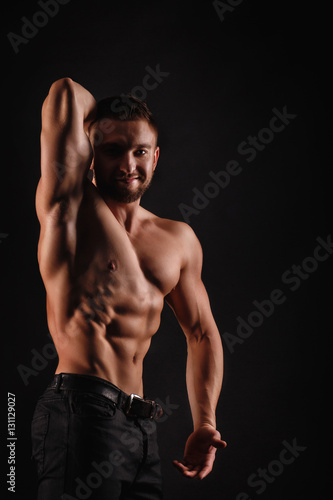 Bodybuilder Posing On A Black Background Dramatic Portrait Of An