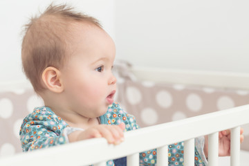 Wall Mural - Eight months old baby girl sucking the side of her bed