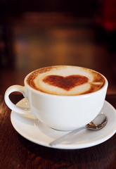 Wall Mural - Cup with hot tasty coffee on wooden table in cafe, close up view